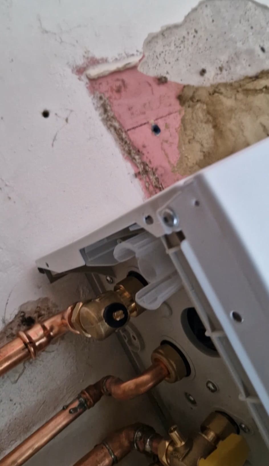 Boiler being mounted on its bracket with copper connections below